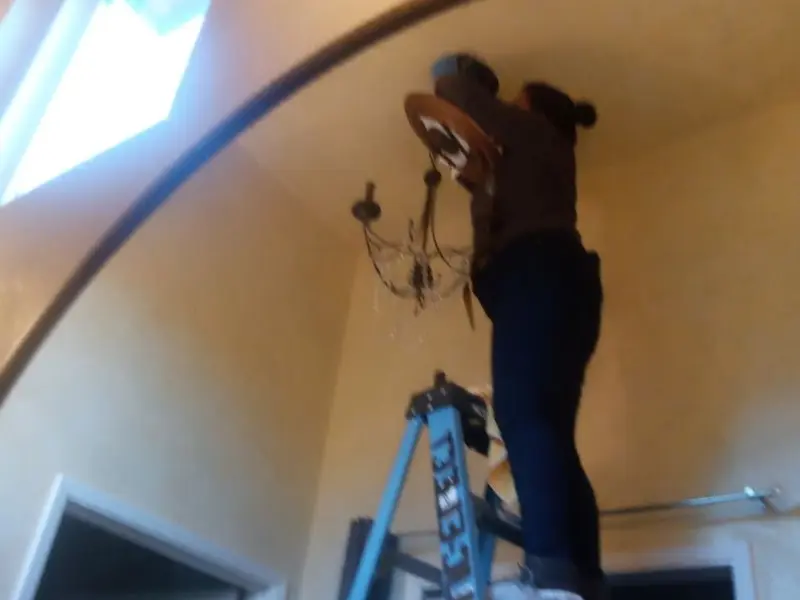 Electrician installing a chandelier in a West Linn residence